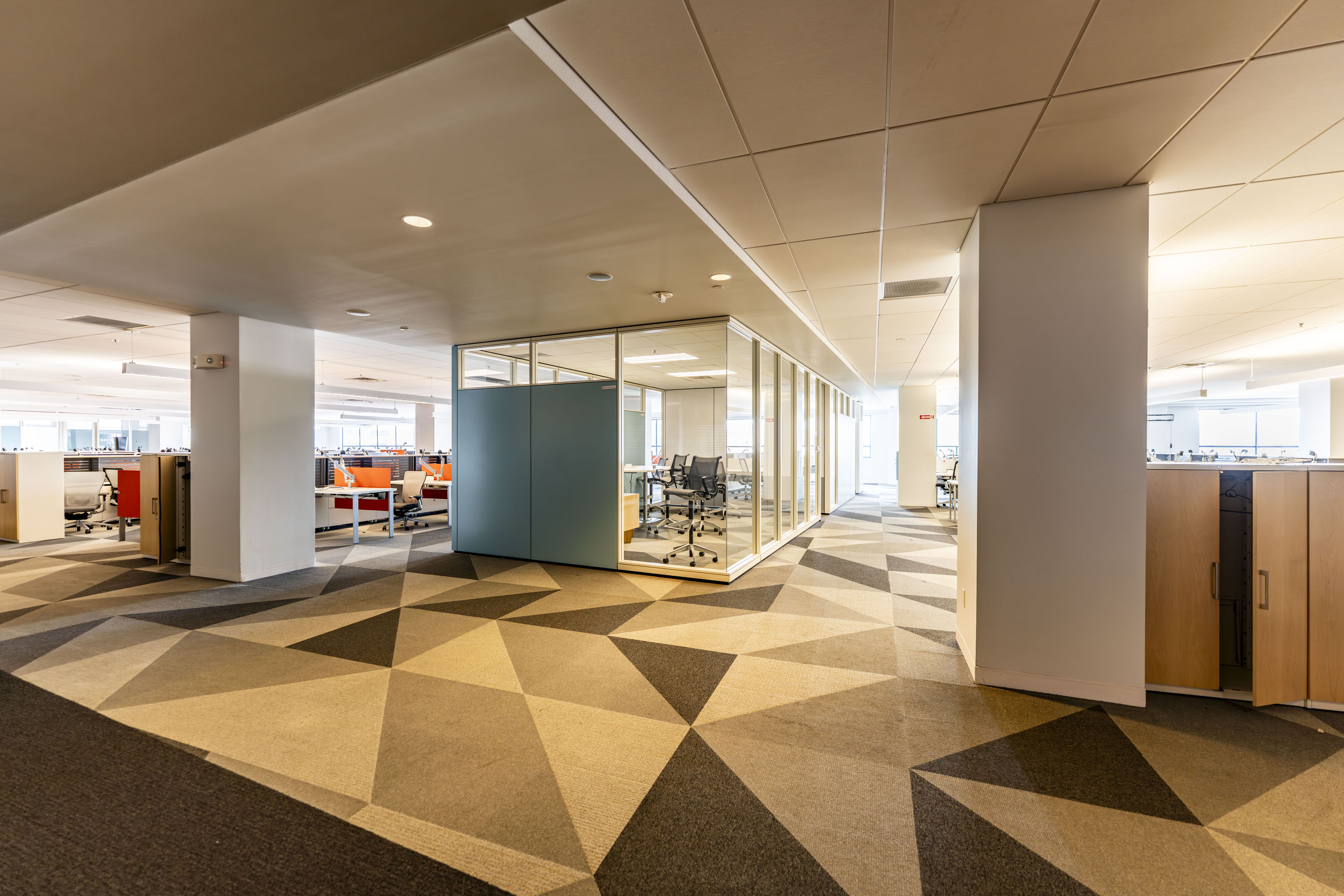 Centennial Building open floor plan office space with geometric carpet, glass conference rooms, and modern workstations